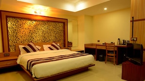 A modern hotel room with a large bed, a desk, and a television.