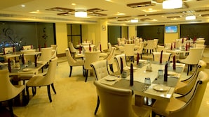 A restaurant with multiple dining tables and chairs, each set with plates, glasses, and cutlery.