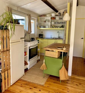 A compact kitchen with a stove, oven, and sink, wooden flooring, and a green countertop.