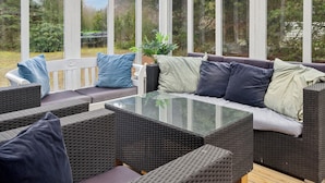 A covered outdoor seating area with wicker furniture and a glass-top table.
