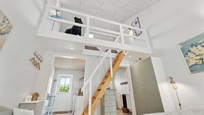 Een slaapkamer in loftstijl met een houten trap, een hoogslaper, een bureau en uitzicht op de keuken.