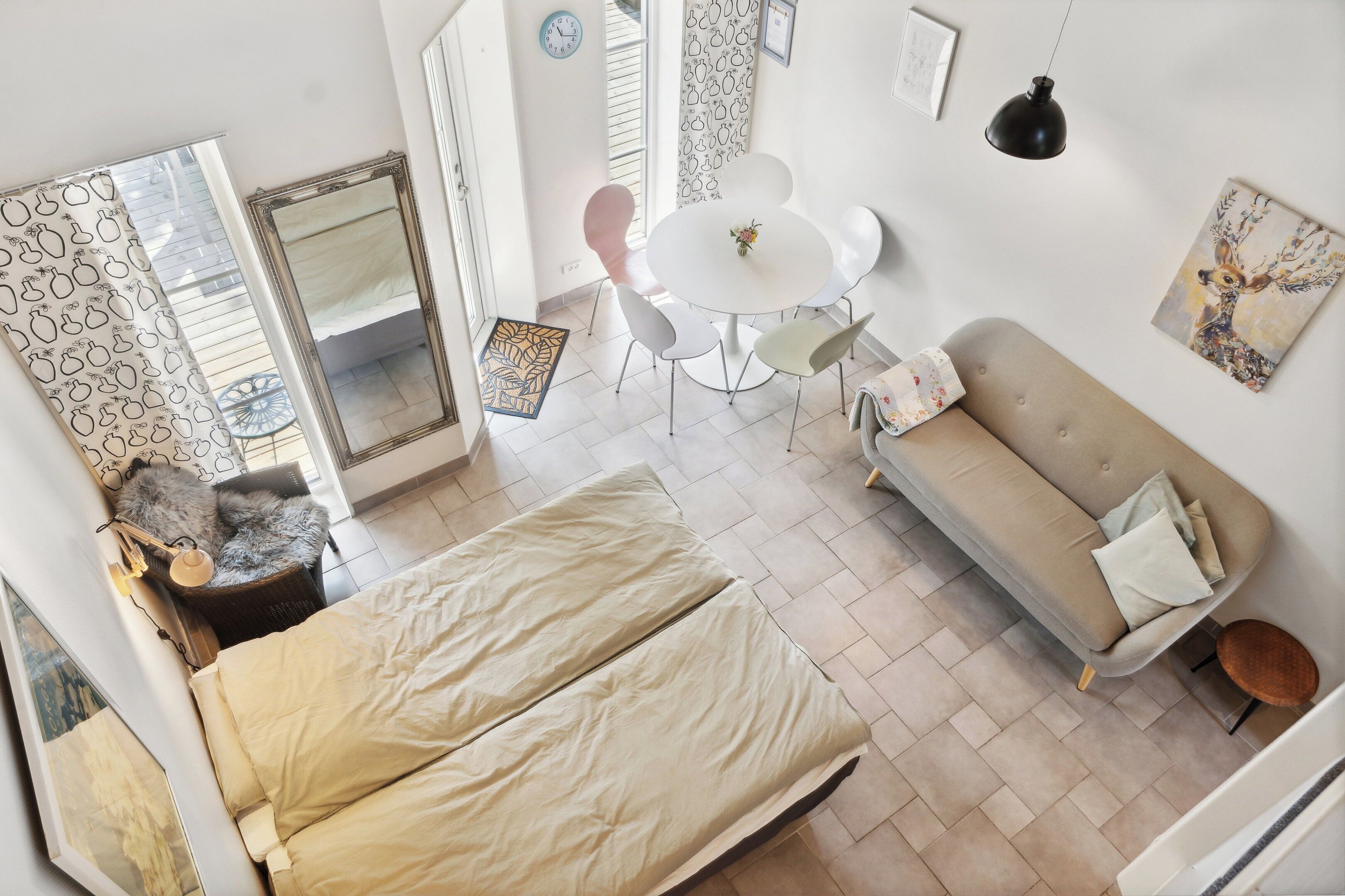 Une chambre à coucher comprenant un lit, un canapé, une table à manger avec des chaises, un miroir et une horloge murale.