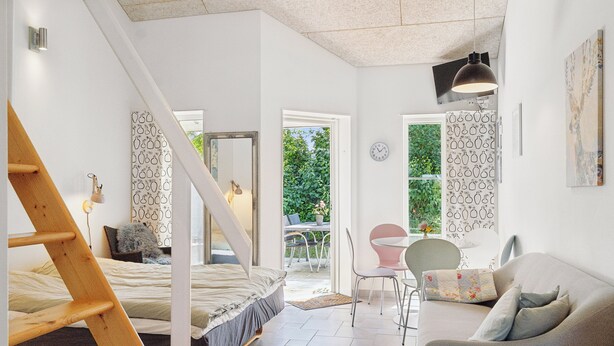 Een slaapkamer met een bed, een houten trap, een bureau, een stoel en een raam.
