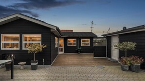 Un immeuble résidentiel doté d’un patio couvert, de plantes en pot et d’un chemin en briques.