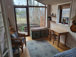 Una habitación acogedora con un banco de madera, una silla de mimbre y una mesa.