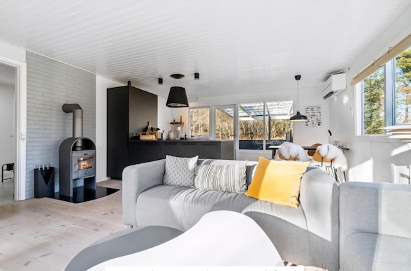 A modern living room with a sofa, a fireplace, and a kitchen area in the background.