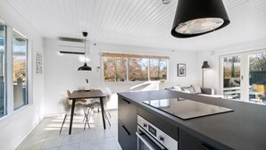 A modern kitchen with a central island, pendant lighting, and a view of the outdoors.