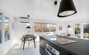 A modern kitchen with a central island, pendant lighting, and a view of the outdoors.
