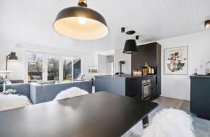 A modern kitchen with a central island, pendant lighting, and a view to the outside.
