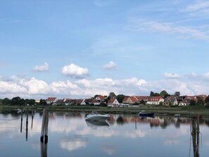 Ein stiller See mit Booten, einem klaren Himmel und HĂ€usern im Hintergrund.