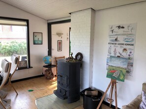 Ein Zimmer mit Kaminofen, Globus, einem GemÀlde auf Staffelei und einem Poster an der Wand.