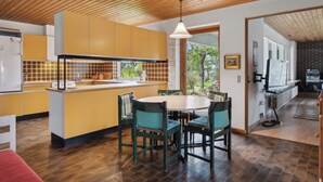 Una cocina moderna con techo de madera, armarios amarillos, una mesa de comedor con sillas y vistas al exterior.
