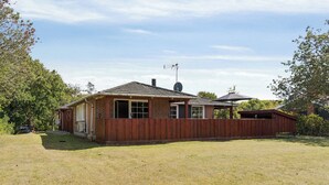 Une maison de plain-pied en briques, dotée d’une cour arrière clôturée, d’une antenne parabolique et d’un patio couvert.