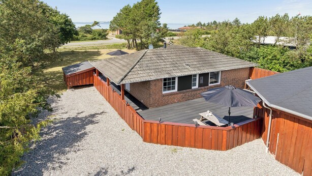 Il s’agit d’une propriété résidentielle comprenant une maison en briques, une terrasse en bois et une allée gravillonnée.