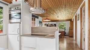 Une cuisine moderne avec des meubles blancs, un four Bosch et un plafond en bois.