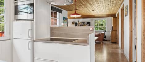 A modern kitchen with white cabinetry, a Bosch oven, and a wooden ceiling.