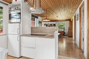 Une cuisine moderne avec des meubles blancs, un four Bosch et un plafond en bois.