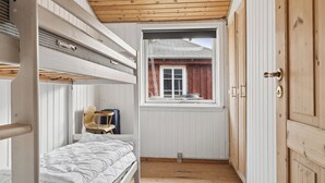 A compact room with a bunk bed, a small table, and a window with a view of a building outside.