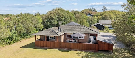 A single-story house with a covered patio area, a chimney, and a fenced yard.