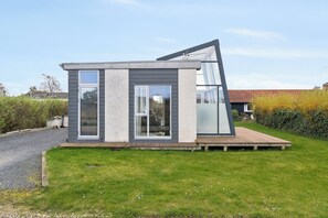 Ein modernes Haus mit Satteldach, großen Fenstern und einer Holzterrasse.