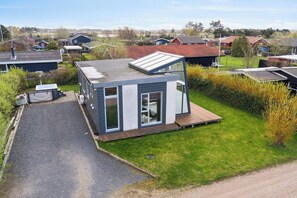 Una casa moderna con techo plano, un ventanal grande y una pequeña terraza.