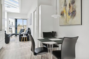 Ein moderner Essbereich mit Tisch, Stühlen, einer Couch und einem Gemälde an der Wand.