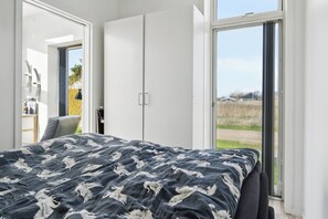 Ein Schlafzimmer mit einem Bett, einem Kleiderschrank und einer Glastür zum Außenbereich.