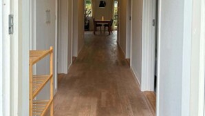 Un corridoio con pavimento in legno, un tappeto nero e un lampadario.
