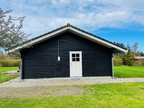 A black wooden building with a white door and a small porch area.