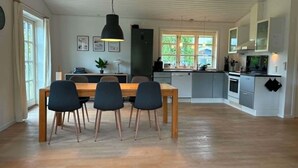 Una cucina moderna con zona pranzo, pavimento in legno e un'ampia finestra.
