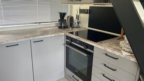 A compact kitchen with a built-in oven, a coffee maker, and a microwave.