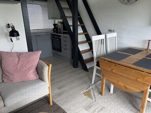 Ein Loft-Zimmer mit Esstisch, einer Couch, einer Treppe und einer Küchenzeile.
