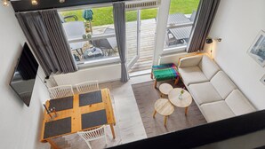 A modern interior with a dining area, sofa, and a view of the outdoors.