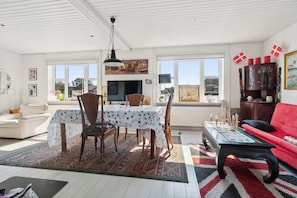 A spacious living area with a dining table, chairs, a red sofa, and a television.