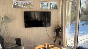 A living room with a wooden ceiling, a flat-screen TV, a round coffee table, and a sofa. - Cozy house with outdoor spa. (Væggerløse)