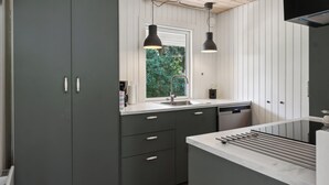 A modern kitchen with grey cabinets, a window, and pendant lights. - Cozy house with outdoor spa. (Væggerløse)