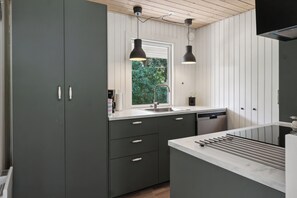 Een moderne keuken met grijze kastjes, een raam en hanglampen.