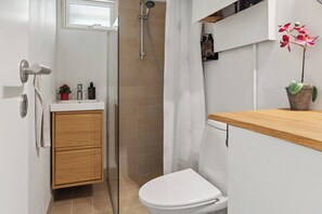 Een badkamer met een douche, toilet, wastafel en een potorkidee.