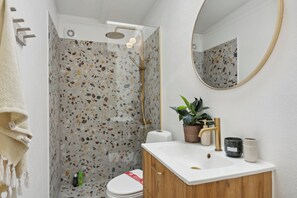 Ein Badezimmer mit Dusche, Toilette, Waschbecken und Spiegel.