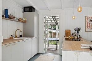 A kitchen with white cabinets, a wooden countertop, a sink, and a dining area with a table and chairs.