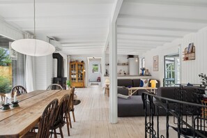 A spacious living area with a wooden dining table, a sofa, and a fireplace.