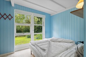 Ein Schlafzimmer mit Bett, Fenster und Blick ins Grüne.