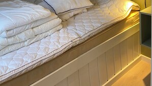 A bunk bed with white bedding, a bedside lamp, and a wall-mounted shelf. - Holiday Cottage in Harbor Town of the Year (Allinge)