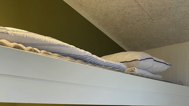 A bunk bed with white bedding, a bedside lamp, and a small shelf. - Holiday Cottage in Harbor Town of the Year (Allinge)