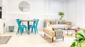 A modern living room with a sofa, coffee table, and a dining area with chairs and a table. - Beco Santa Emilia 2I, a Home in Madeira (Funchal)
