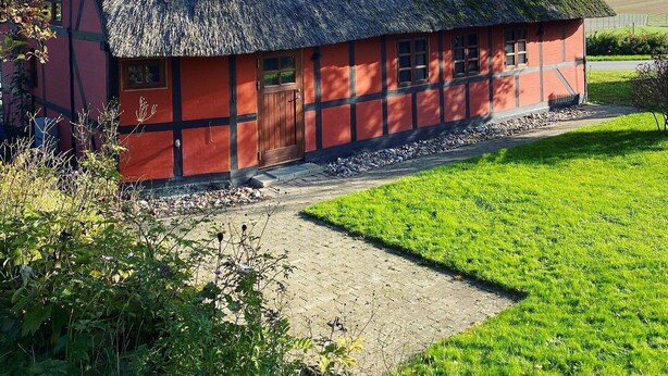 A traditional thatched-roof house with a red exterior, a chimney, and a well-maintained garden. - Charming cottage in the best H.C. Andersen style (Frørup)
