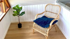 A corner room with a wicker chair, a potted plant, wooden flooring, and white paneled walls. - Charming cottage in the best H.C. Andersen style (Frørup)