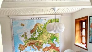 A room with a large map of Europe, a table with chairs, a hanging light fixture, and a window with a view. - Charming cottage in the best H.C. Andersen style (Frørup)