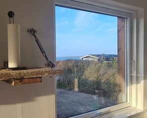 A window with a view of a house and a body of water.