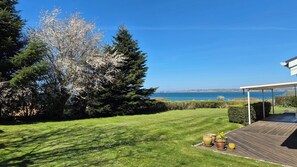 A well-maintained lawn, a wooden deck, and a view of the sea.